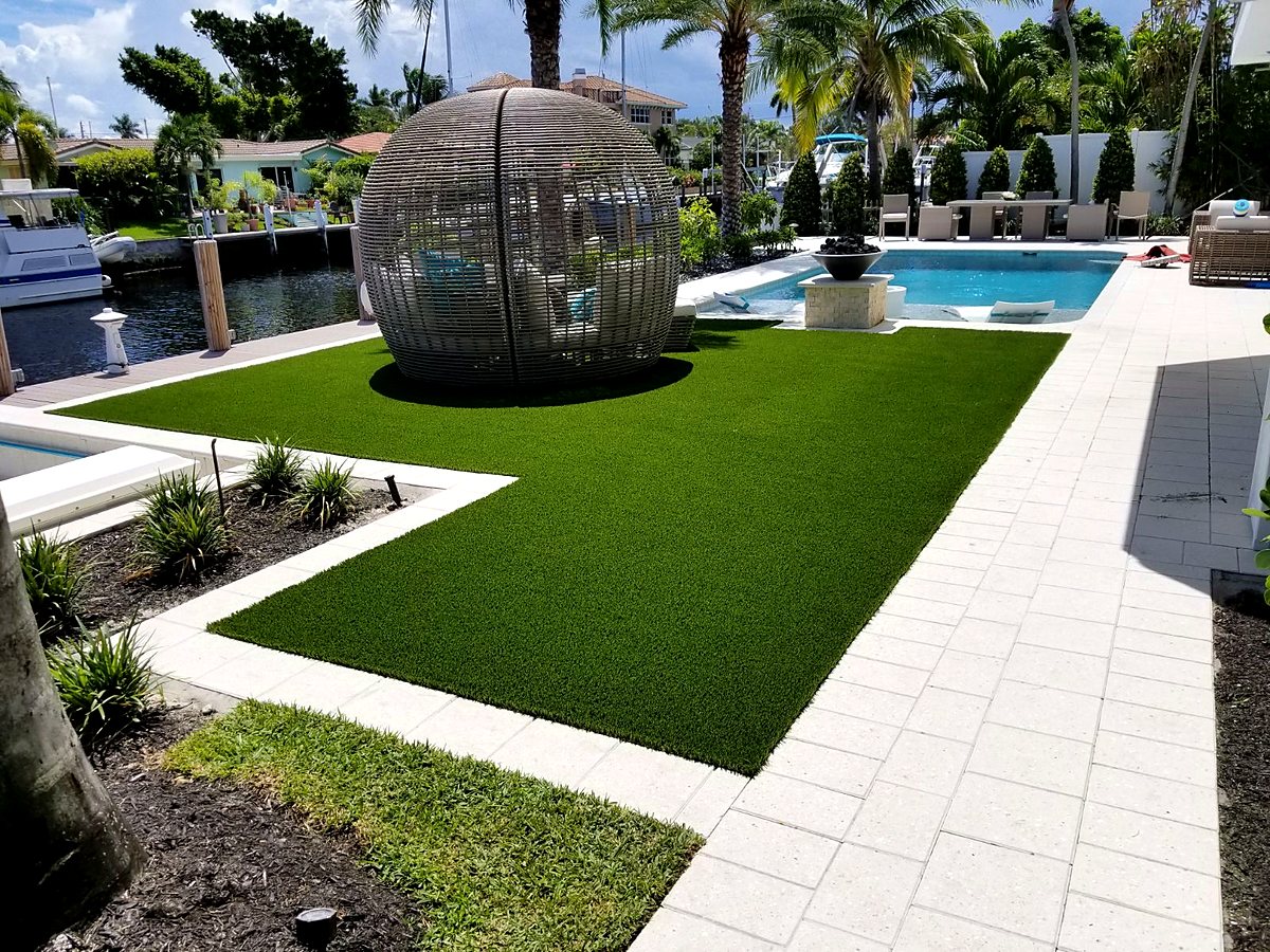 Waterfront backyard lawn beside a pool and paver deck